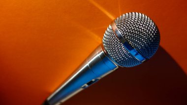 Gümüş renkli stüdyo mikrofonu. Kopyalama alanı olan turuncu arkaplan