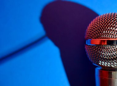 Gümüş renkli stüdyo mikrofonu. Kopyalama alanı olan mavi arkaplan