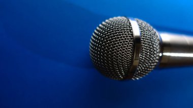 Gümüş renkli stüdyo mikrofonu. Kopyalama alanı olan mavi arkaplan