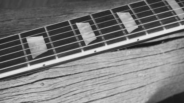 Electric guitar neck on the wooden boards . Black and white