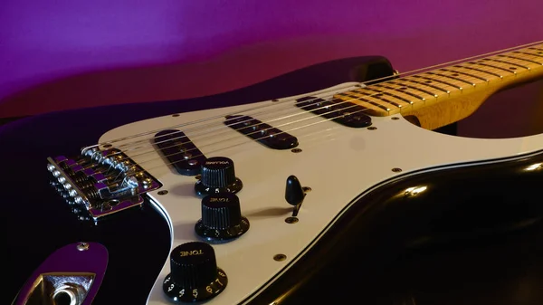 Electric guitar closeup . Purple  background