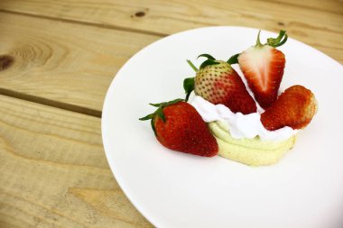 Tahta masadaki kremalı lezzetli çileklerin olduğu telif alanı 