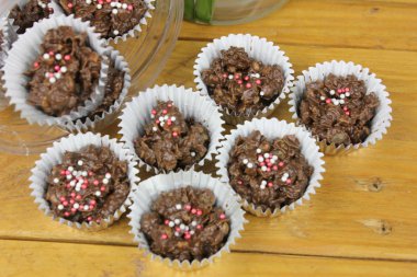 Tahta zemin üzerinde şeker taneleri olan lezzetli çikolatalı kekler.