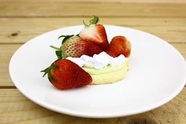 Tahta masadaki kremalı lezzetli çileklerin olduğu telif alanı 