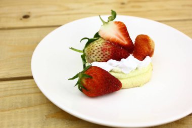 Tahta masadaki kremalı lezzetli çileklerin olduğu telif alanı 