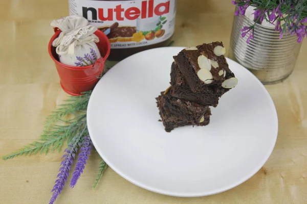 Вкусный Кусок Шоколадного Торта Нутеллой Цветы Заднем Плане — стоковое фото