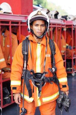 İtfaiye memuru tam teçhizatla itfaiye arabasının yanında duruyor.