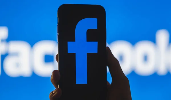 Logo de Facebook en la pantalla del smartphone en la mano . —  Fotos de Stock