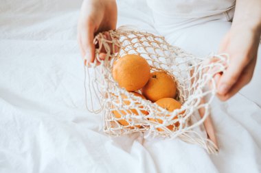 Kadın eco çantasından portakal alıyor..