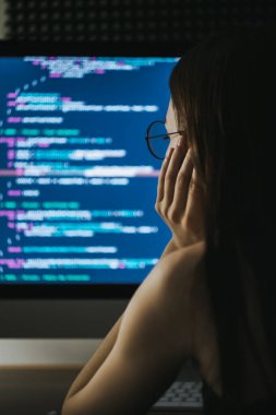 Genç bayan programcı bir bilgisayara program kodu yazar.. 