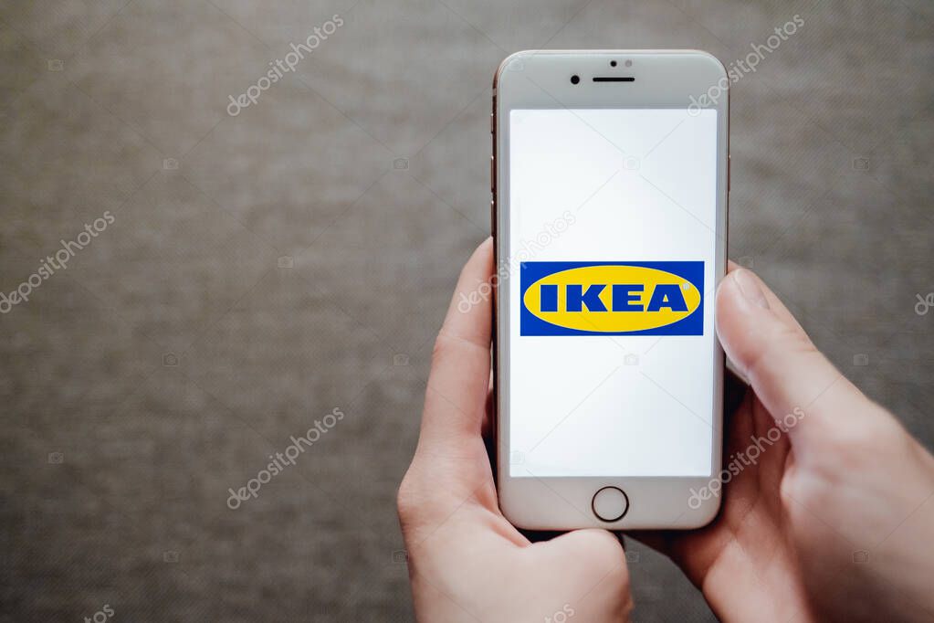 Hands holding the iphone with ikea logo on the screen.
