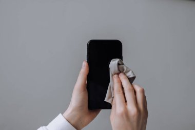 Akıllı telefon ekranını lifli bir bezle temizliyorum..