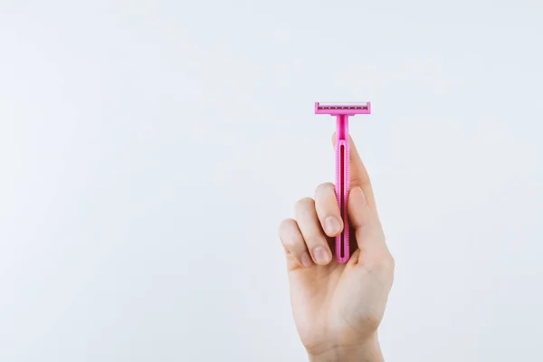 Female hand takes pink disposable razor. — Stock Photo, Image