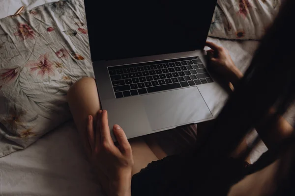 Fiatal nő ül az ágyon, és használja laptop. — Stock Fotó
