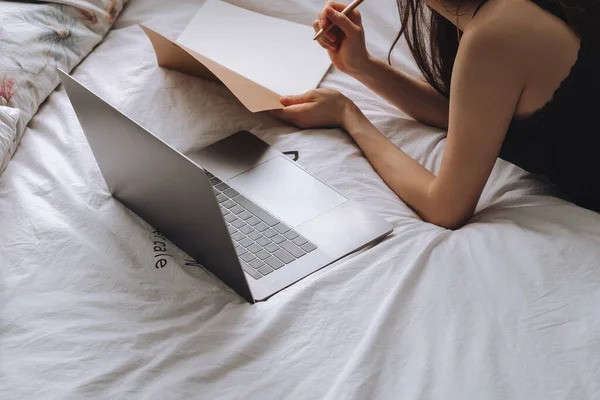Fiatal nő fekszik az ágyban laptop és notebook. — Stock Fotó