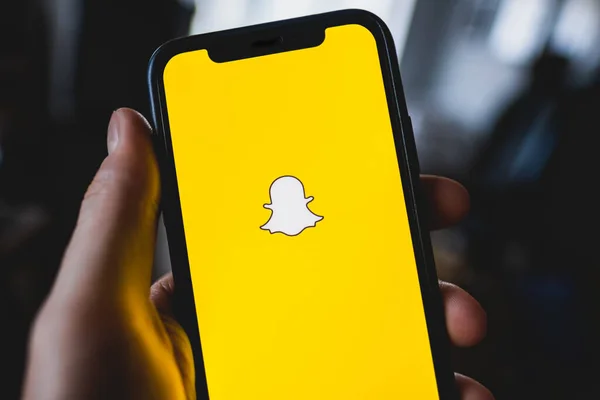 Snapchat logotipo do aplicativo na tela do smartphone na mão . — Fotografia de Stock