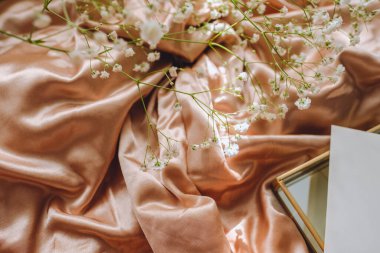 Altın saten kumaşın üzerinde beyaz çigila çiçekleri.