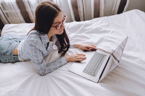 Женщина на кровати в течение дня работает с ноутбуком
.