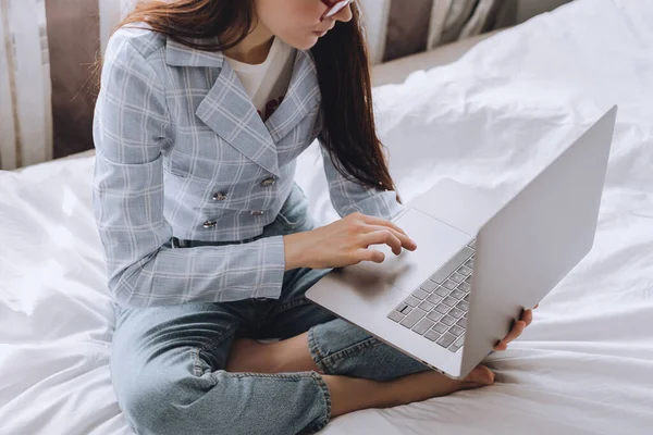 Nő az ágyon napközben dolgozik egy laptop. — Stock Fotó