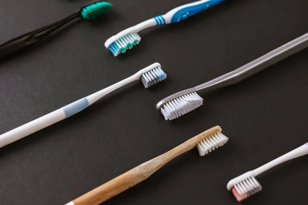 Different types of toothbrushes on a black background. — Stock Photo, Image
