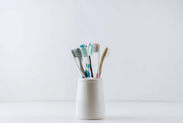 Different types of toothbrushes in a white cup. — Stock Photo, Image