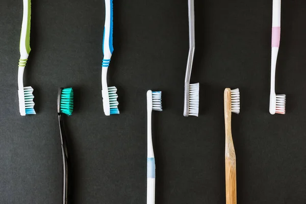 黑色背景上的不同类型的牙刷. — 图库照片
