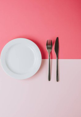 Pembe şeftali arka planında çatal bıçak takımı olan boş beyaz tabak..