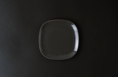 Siyah zemin üzerinde boş koyu gri seramik plaka. 