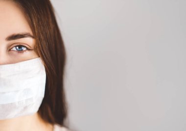 Gri arka planda tıbbi koruyucu maskeli bir kız..