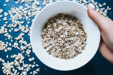 Mavi zemin üzerinde karabuğday lapası olan bir tabağı tutan el..