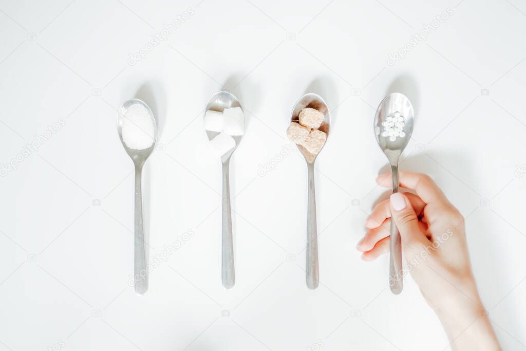 Different types of sugar, the hand holds a spoon with a sugar substitute