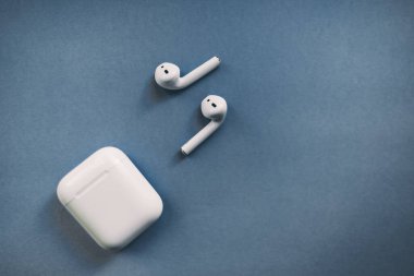Apple AirPods kablosuz kulaklığı. Arkaplanda şarj kutusu var.. 