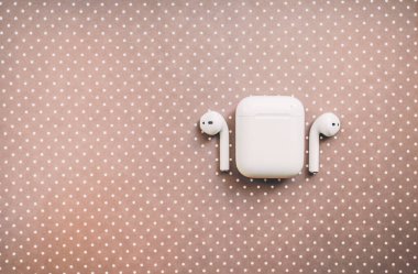 Apple AirPods kablosuz kulaklığı. Arkaplanda şarj kutusu var.. 