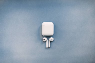 Apple AirPods kablosuz kulaklığı. Arkaplanda şarj kutusu var.. 