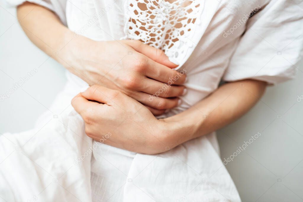Young woman standing holding belly suffering. Pain.