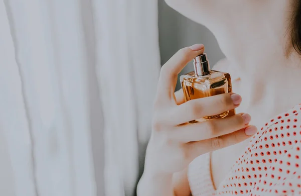 Woman puts on perfume on a white background — Stock Photo, Image