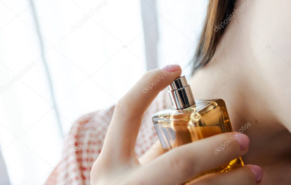 Woman puts on perfume on a white background 
