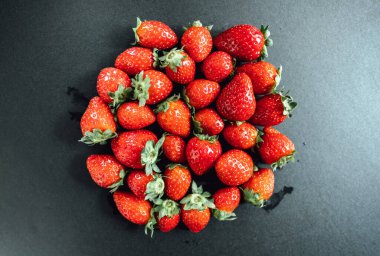 Siyah arka planda taze toplanmış kırmızı çilekler..