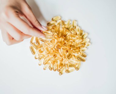 Omega-3 'ün kapsül tabletini tutan eller.