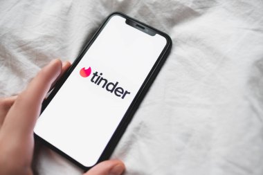 Akıllı telefon ekranındaki Tinder uygulama logosu kadınların elinde.