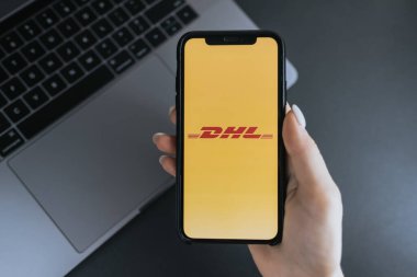 Ekranda DHL logosu olan iPhone X 'i tutarken.