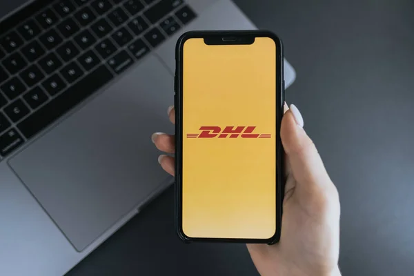 Рука держит iPhone X с логотипом DHL на экране . — стоковое фото