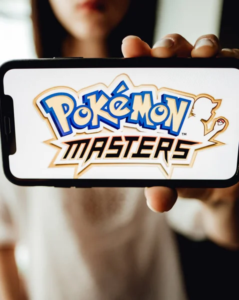 Tangan memegang iPhone dengan Pokemon master di layar. — Stok Foto
