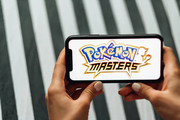 Tangan memegang iPhone dengan Pokemon master di layar. — Stok Foto