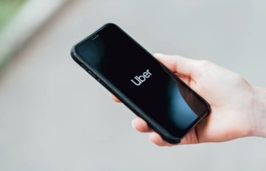 iPhone 'u tutan kız ekranda Uber uygulamasını gösteriyor.
