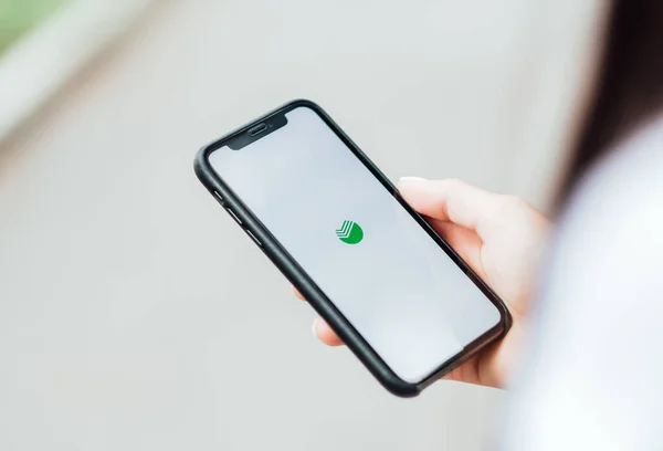 Jovem bela mulher segurando iPhone com tela do aplicativo Sberbank Online . — Fotografia de Stock