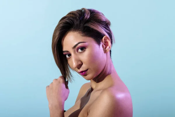 Soft skin beautiful woman with short hair on a blue background iluminated with purple light