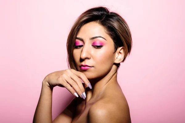 Pembe arka planda yumuşak tenli güzel bir kadının kamera portresine bakıyorum.