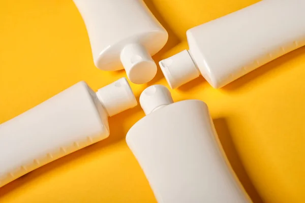 Sarı arka planda dört beyaz şişe.