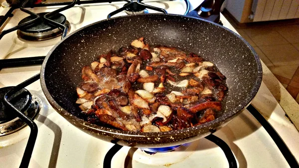 Грибы с луком жарятся на сковороде. — стоковое фото